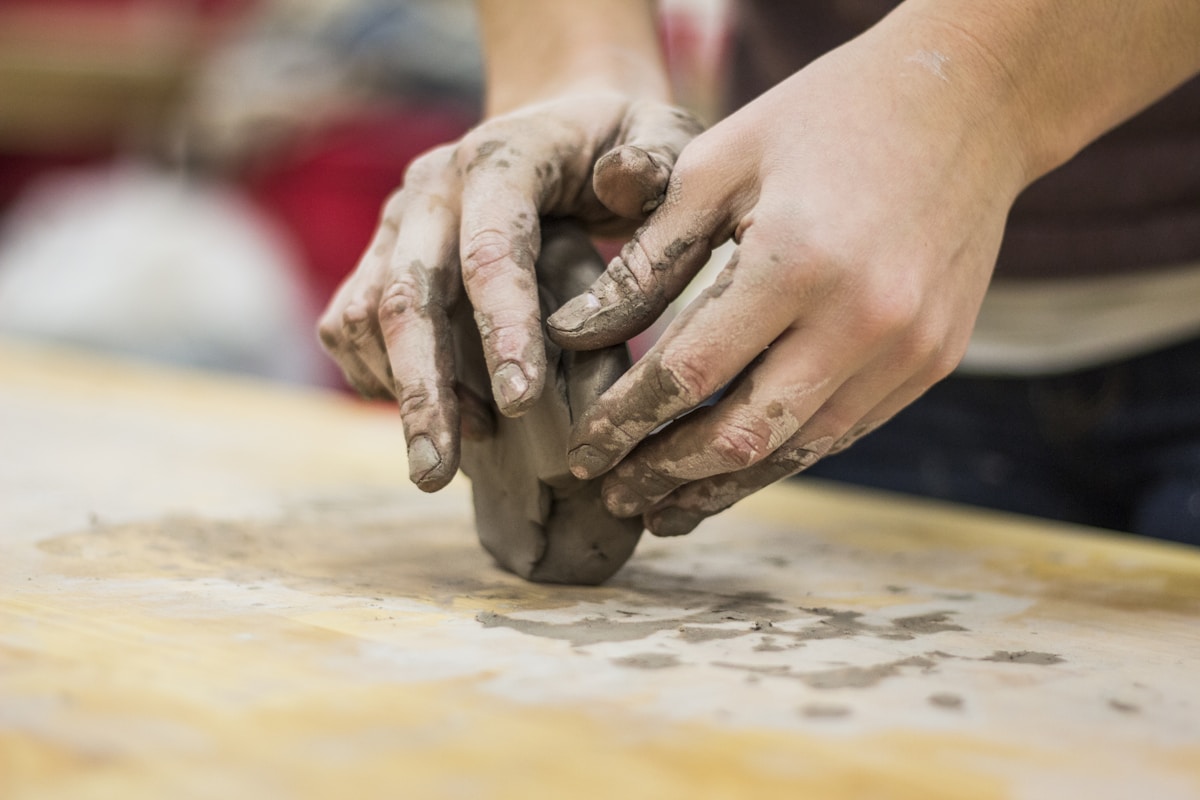 Clay-stained hands of an artisan shaping sacred clay